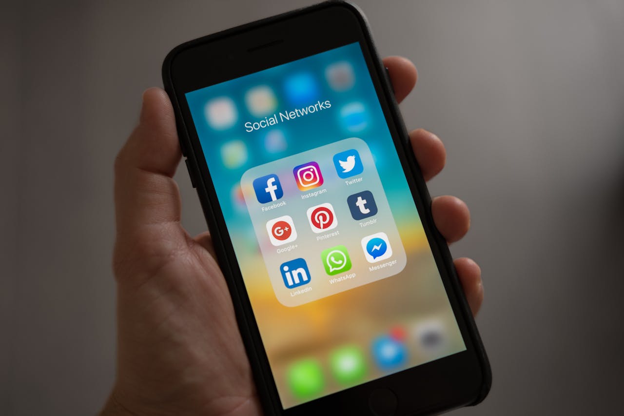 our-services-1 A smartphone displaying various social media icons held in a hand, showcasing modern communication apps.
